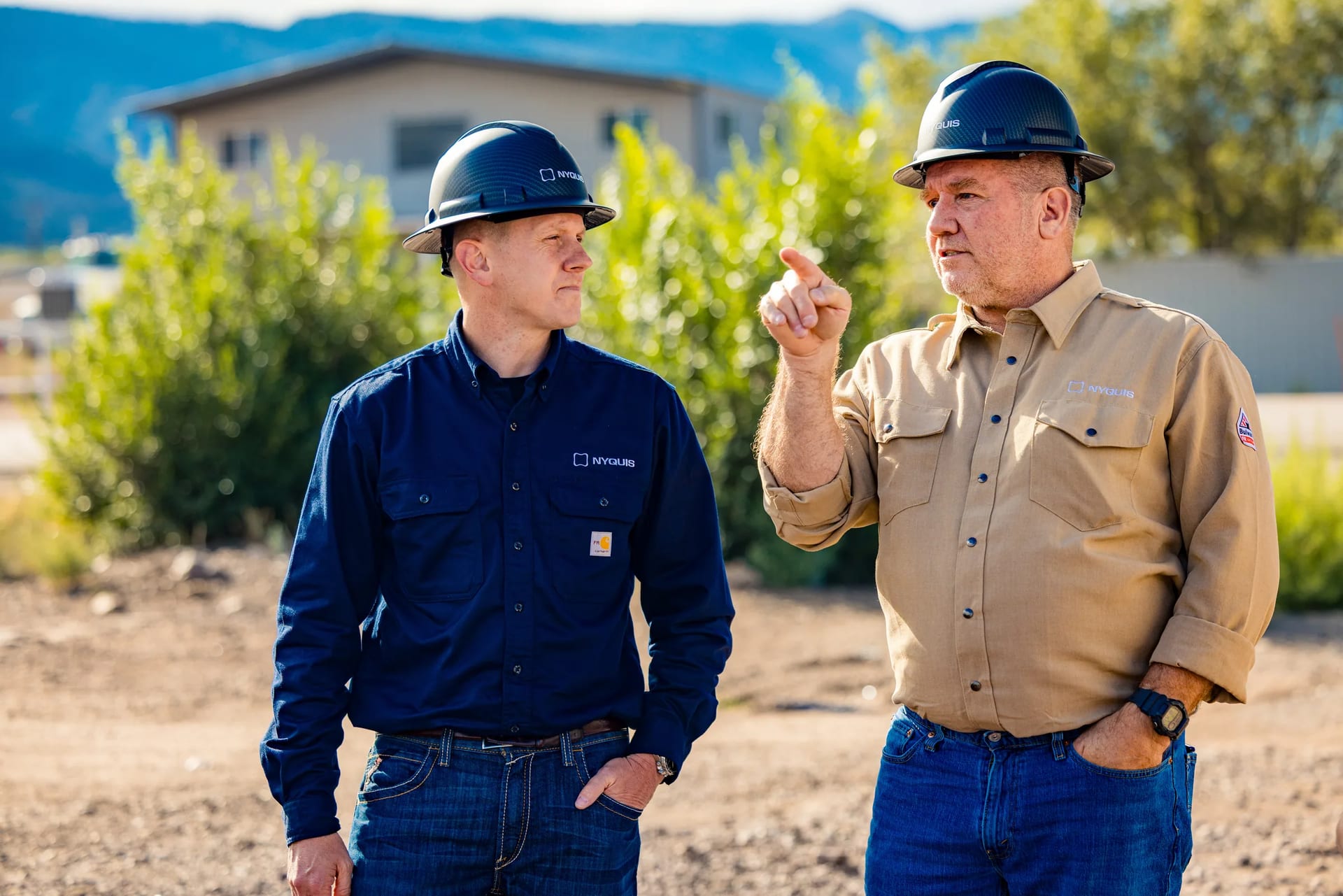 The Nyquis team in branded hard hats and work shirts, talking outdoors