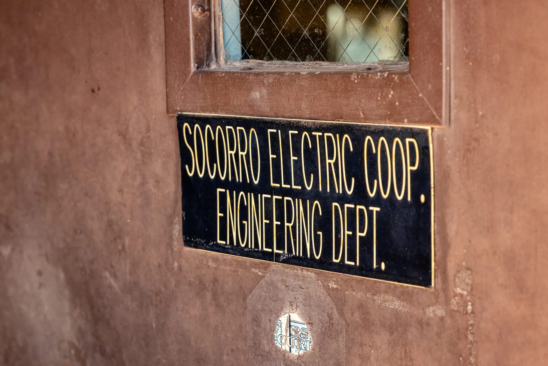 The Socorro Electric Cooperative engineering department sign on a weathered door