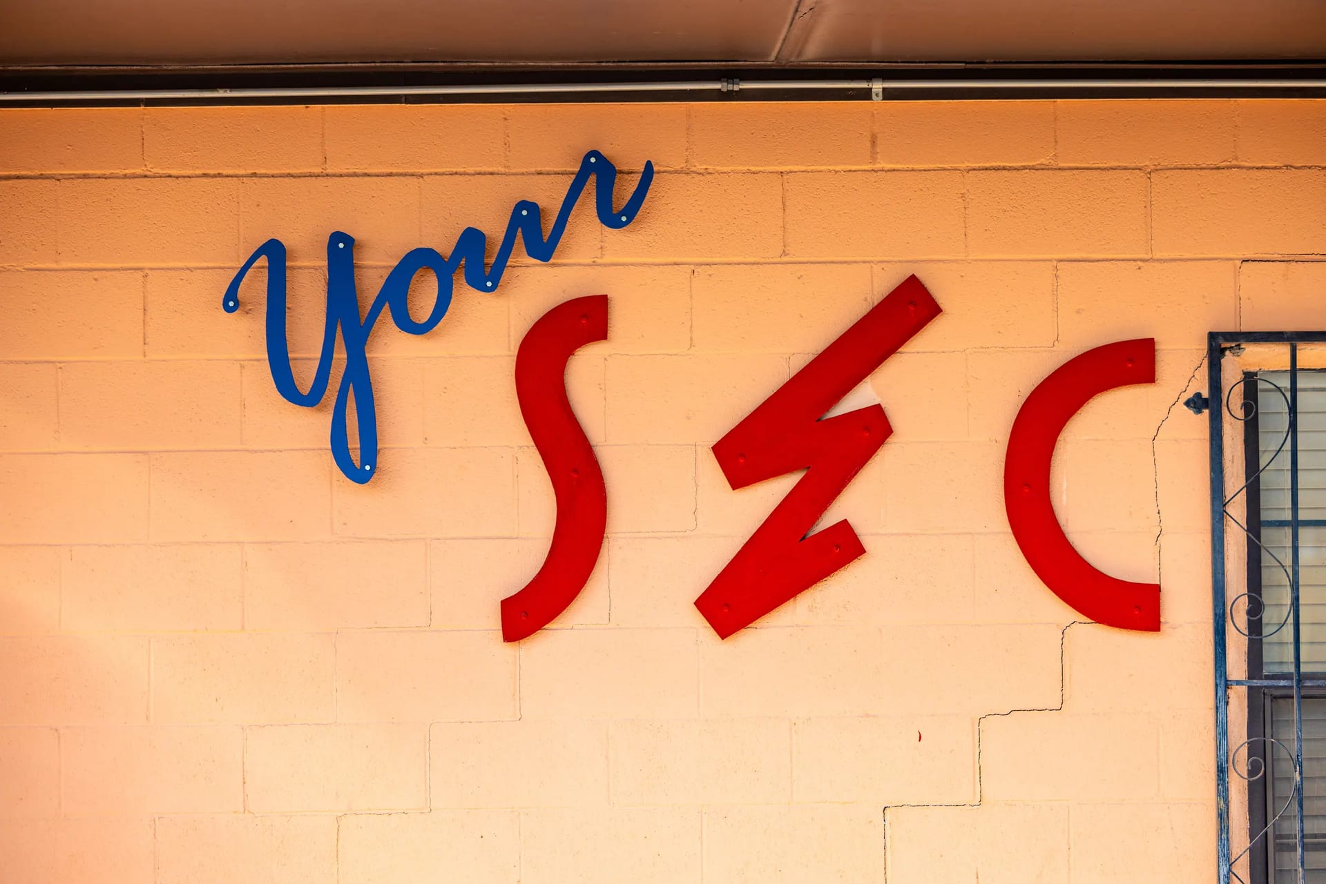The blue and red Socorro Electric Cooperative sign on a sunlit wall
