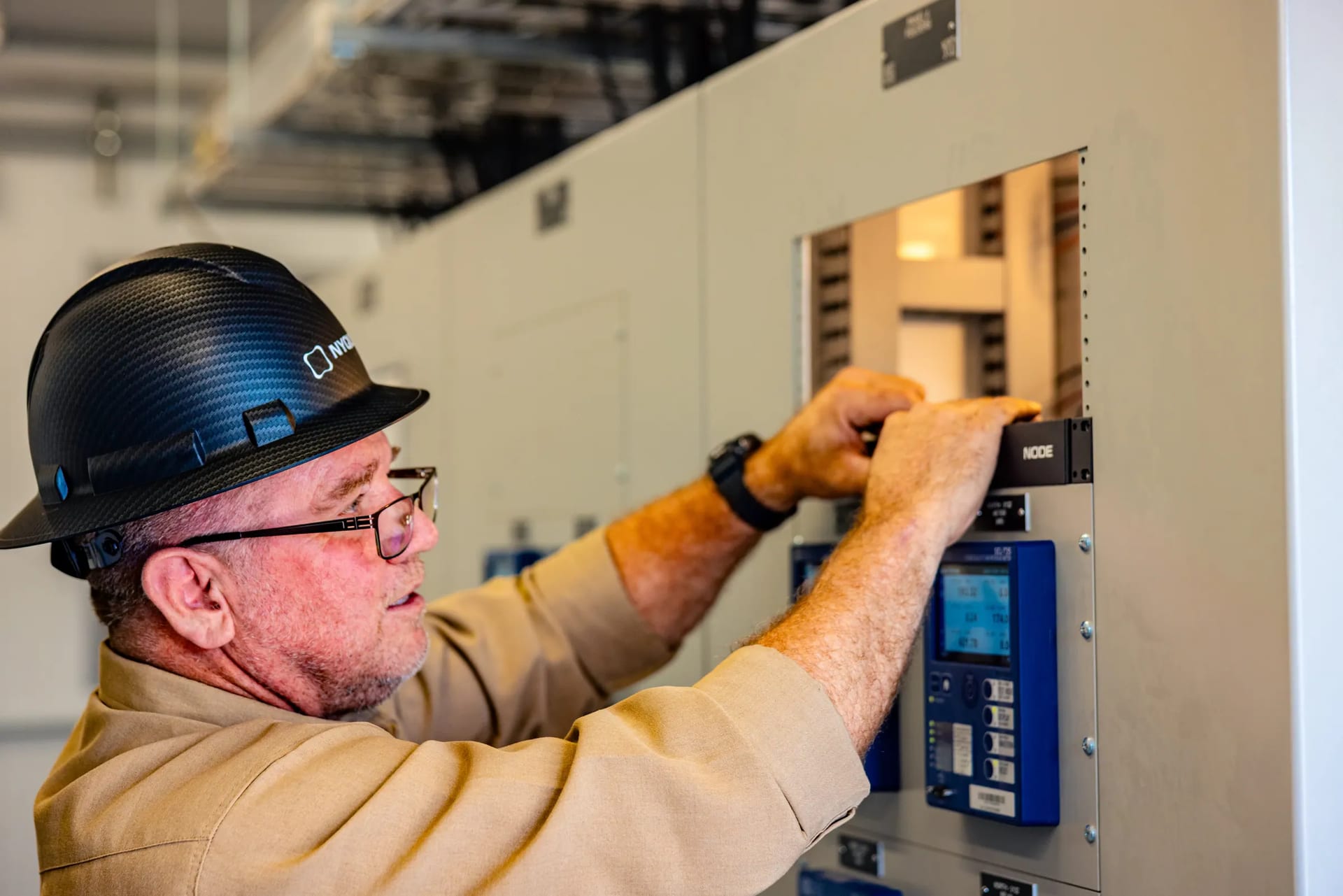 A technician in a Nyquis hard hat installing a Node in a substation equipment cabinet