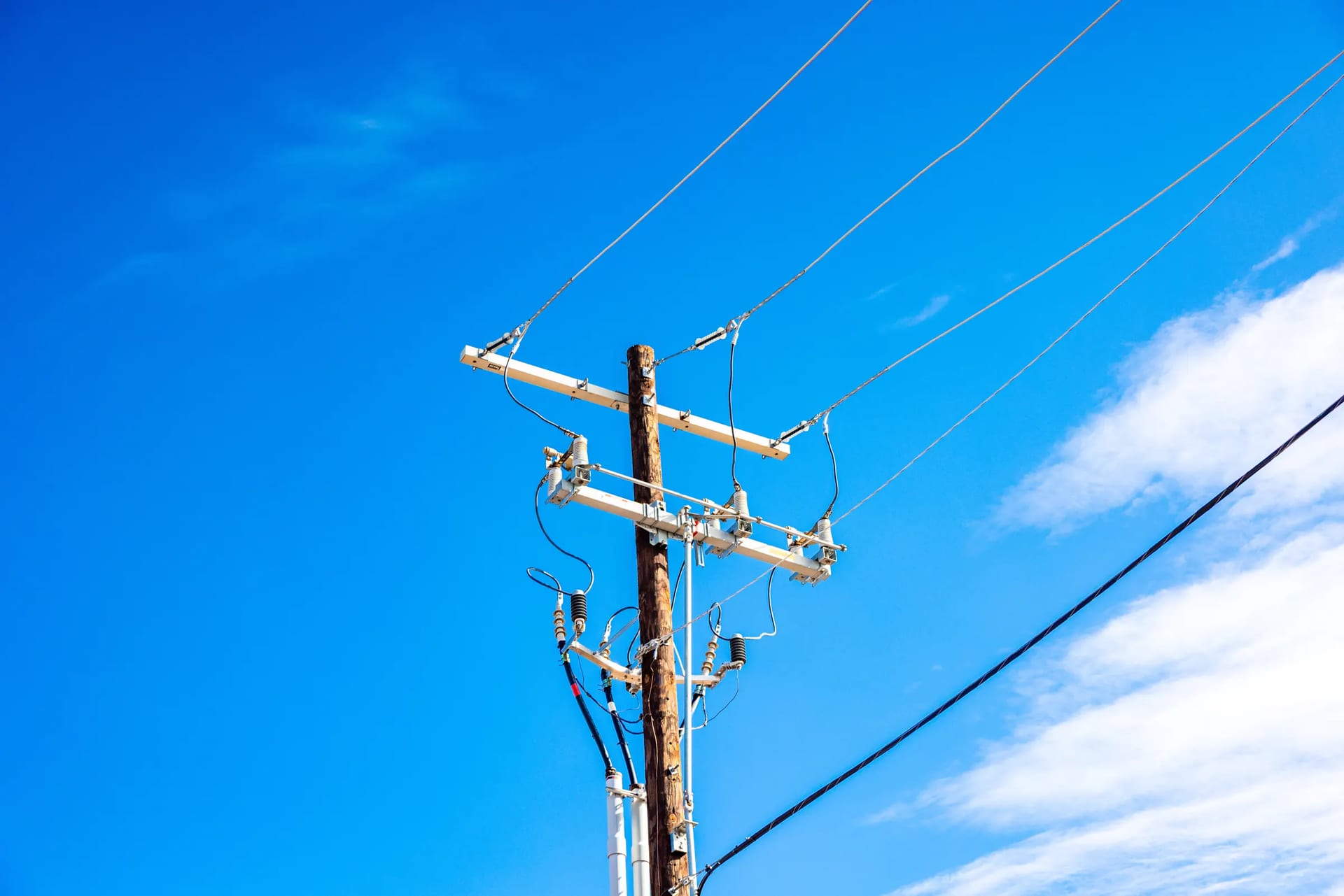 A wooden utility pole and power lines against a bright blue New Mexico sky
